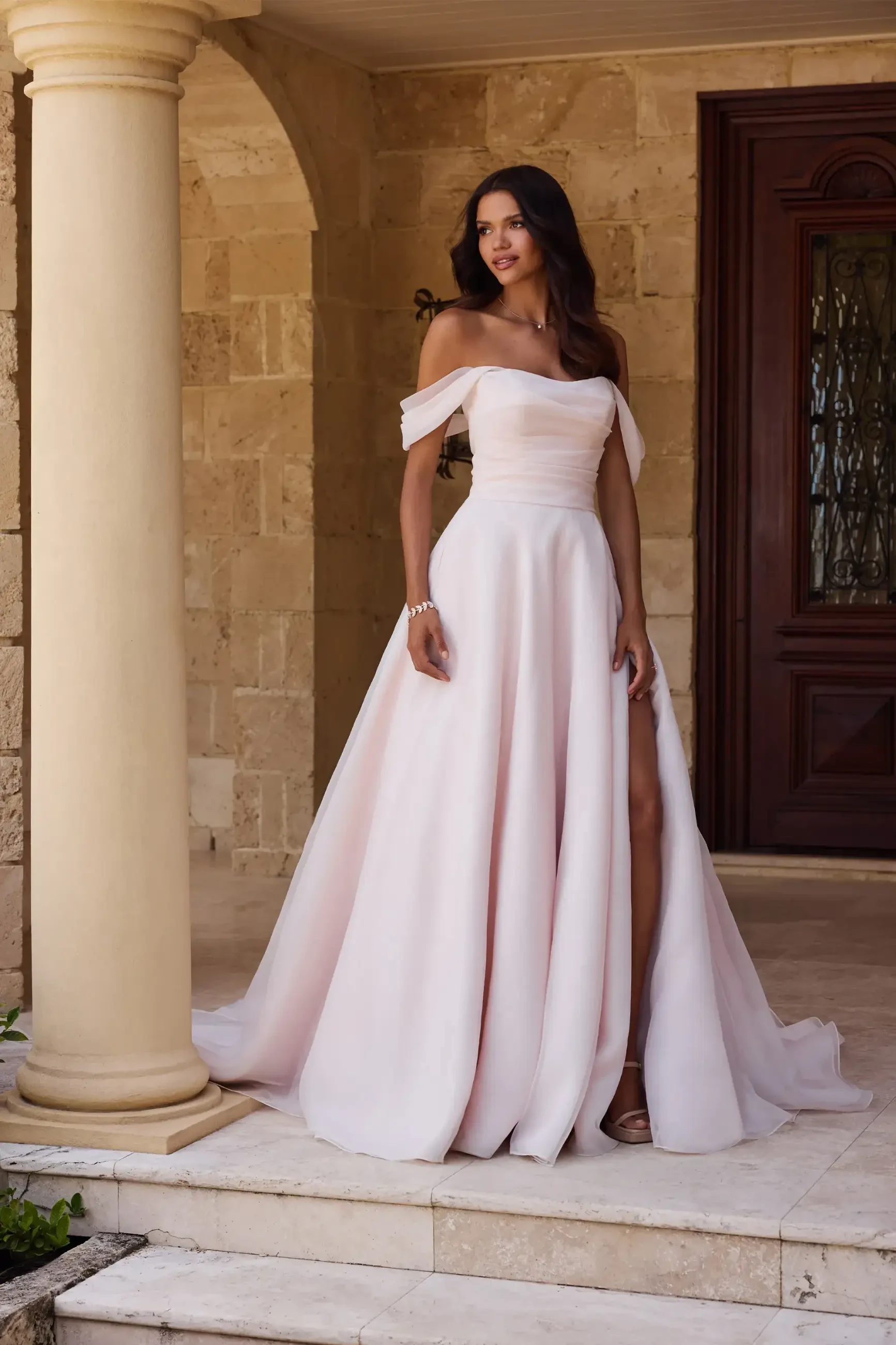 model is wearing an off the shoulder a-line wedding gown
