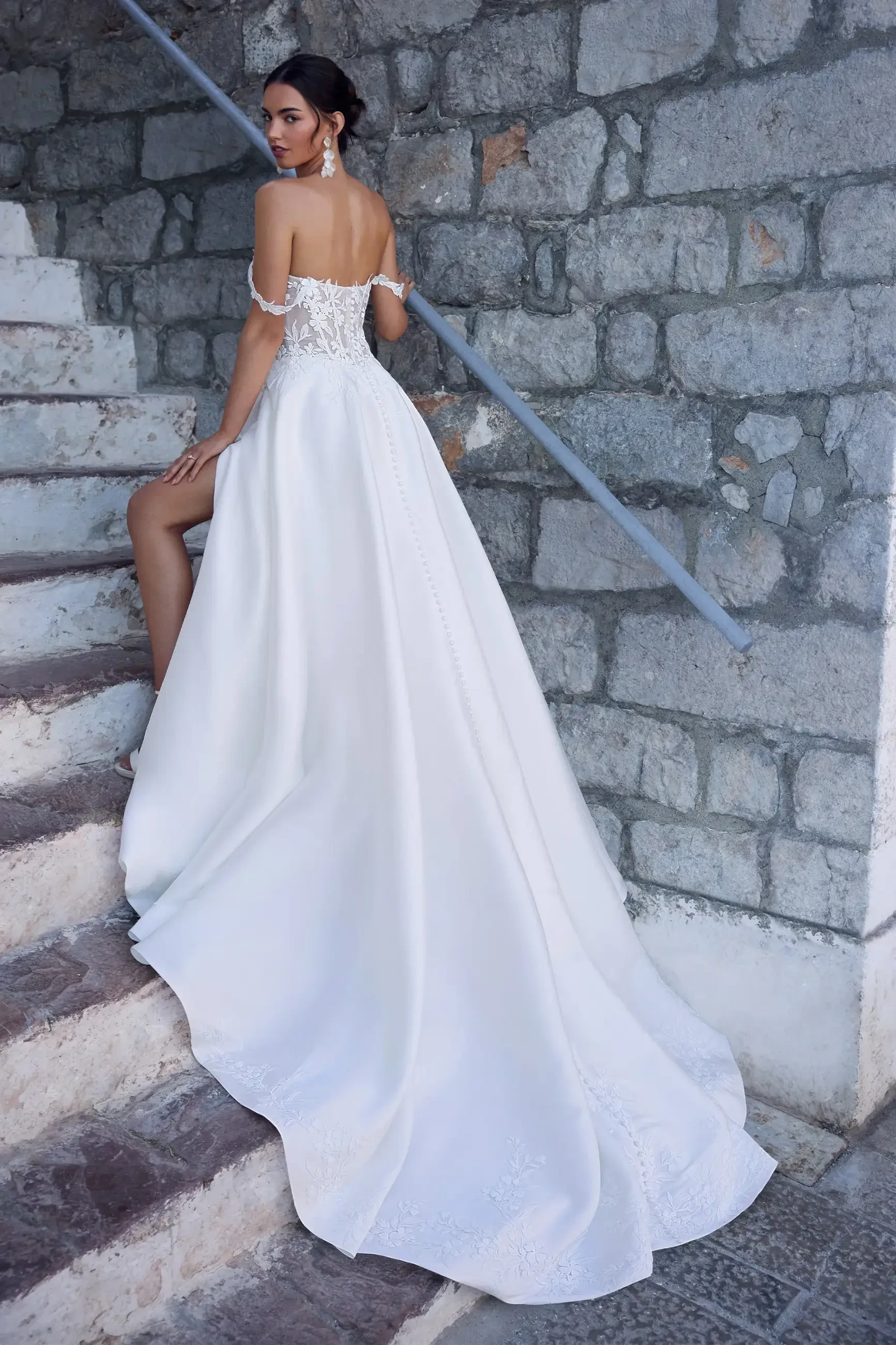 model is wearing an off the shoulder a-line wedding gown by sophia tolli
